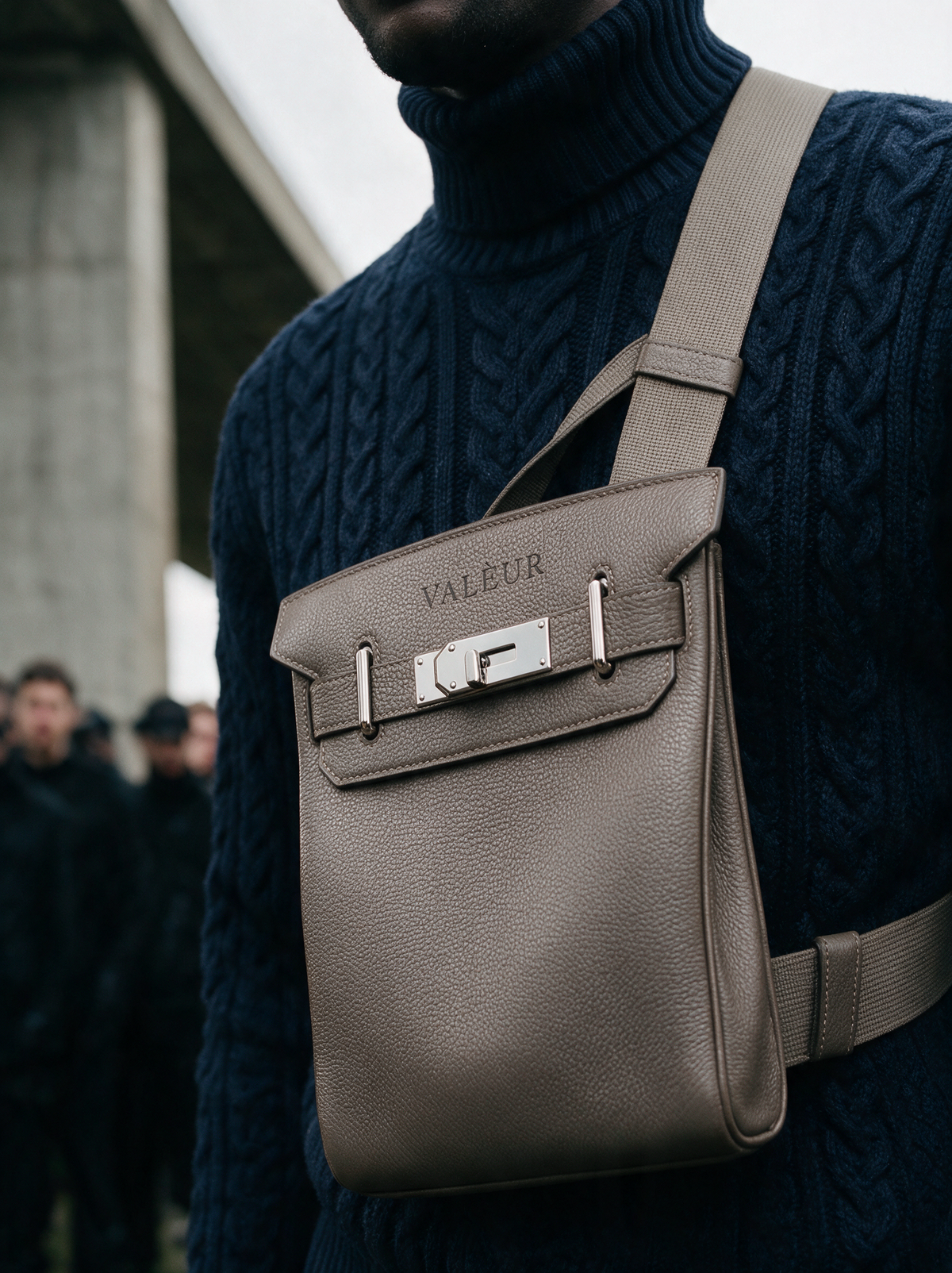 The Sling in Étoupe, worn across a navy cable knit